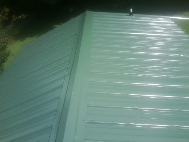 New green metal panels meeting at the ridge of a roof — Flat Roof Repair work by our crew in Parrott