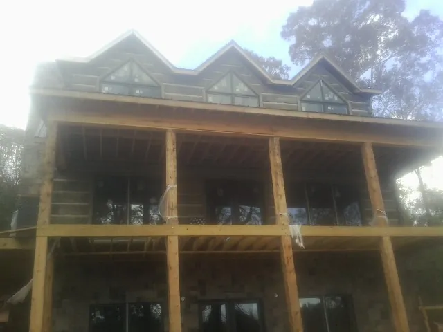 Dormers and porch framing on a large log home under construction — Roof Coating work by our crew in Parrott