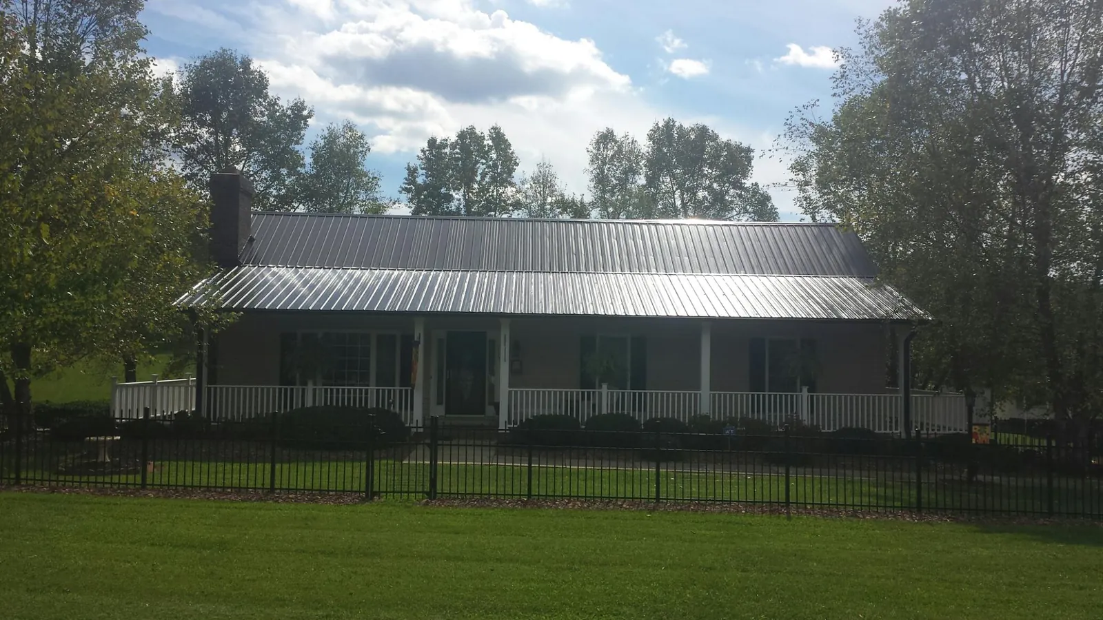 Gray metal roof on a brick ranch with a full width front porch — Gutter Guard Installation work by our crew in Parrott